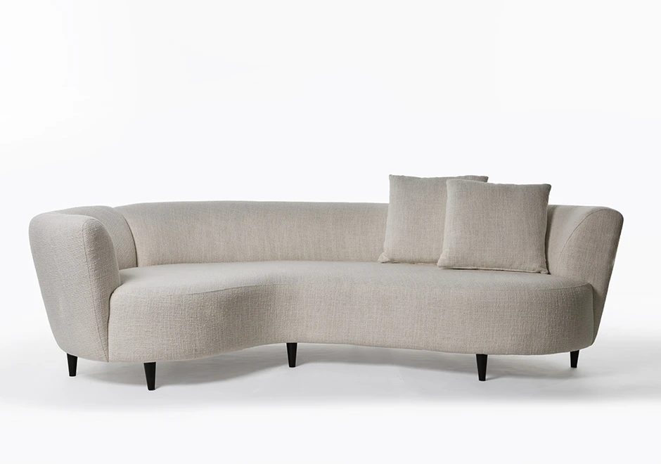 sofá curvo claro com duas almofadas e cinco pés escuros em um fundo branco.