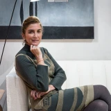 Marina Linhares está sentada em um sofá e está de cabelo preso