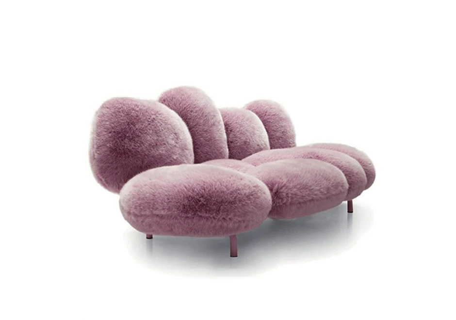 Sofá de design moderno, com estrutura de aço e estofado em pelúcia rosado, visto de lado, em um fundo branco.