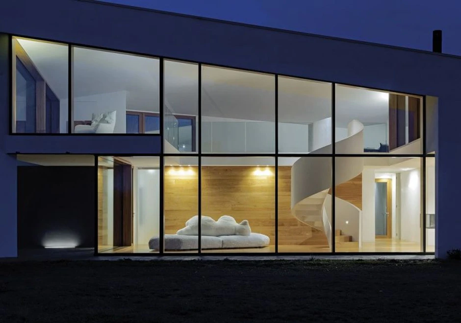 Imagem externa de uma sala com um sofá de design com estrutura de madeira, estofado em plumas e tecido na cor branco, visto de costas, em uma sala clássica.