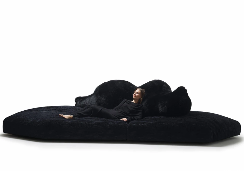 Sofá de design com estrutura de madeira, estofado em plumas e tecido na cor azul, visto de frente, em um fundo branco.