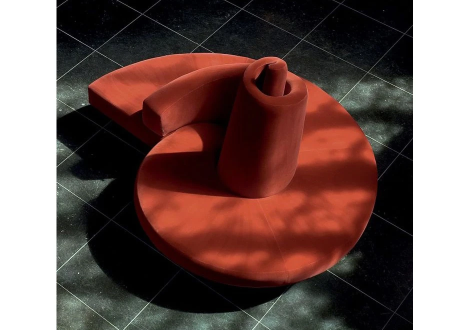 Sofá ilha,com pés em aço cromado e estofado de veludo vermelho, visto de cima em um salão vazio.