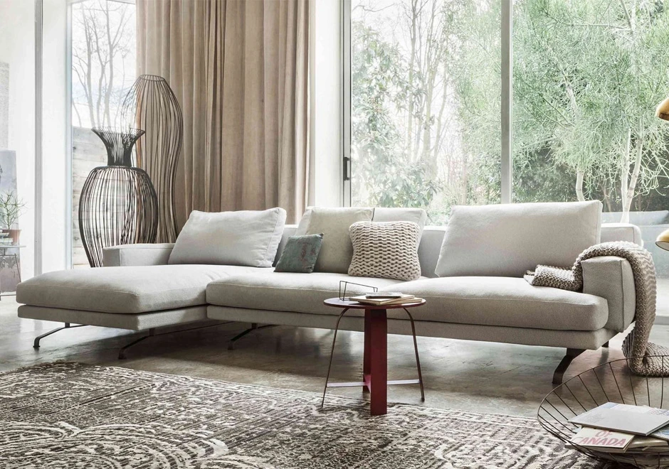 Sofá modular, com estrutura de metal, estofado tecido branco, visto de lado em uma sala moderna.