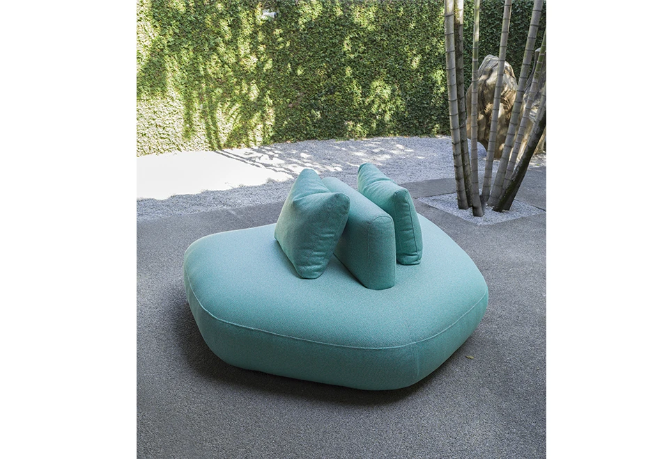 Módulo de sofá Pedras Outdoor com tecidos verde e almofadas decorativas, visto de frente em uma area externa.