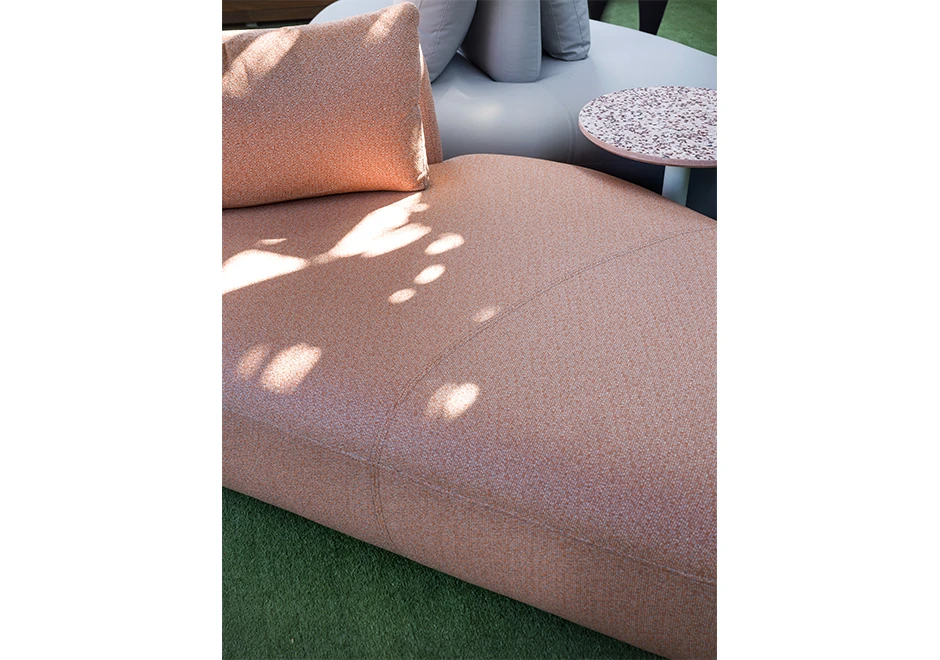 Módulo de sofá Pedras Outdoor com tecidos rosa e almofadas decorativas, visto de frente em uma area externa.