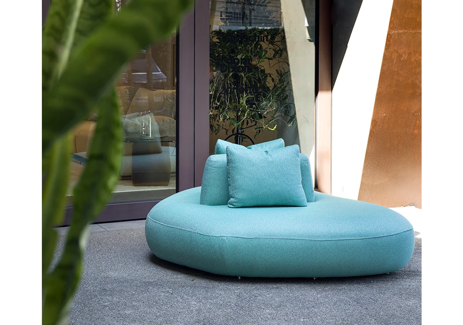 Módulo de sofá Pedras Outdoor com tecidos azul e almofadas decorativas, visto de frente em uma area externa.