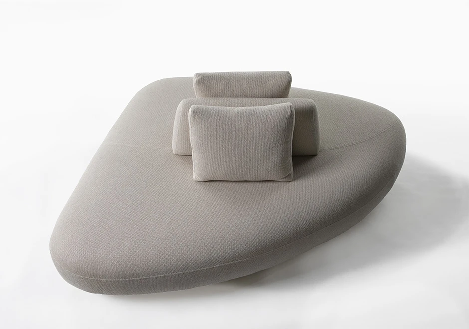 Um módulo de sofá Pedras modular, com estrutura de madeira, com duas almofadas decorativas, estofado em tecido cinza, visto de cima, em um fundo branco.