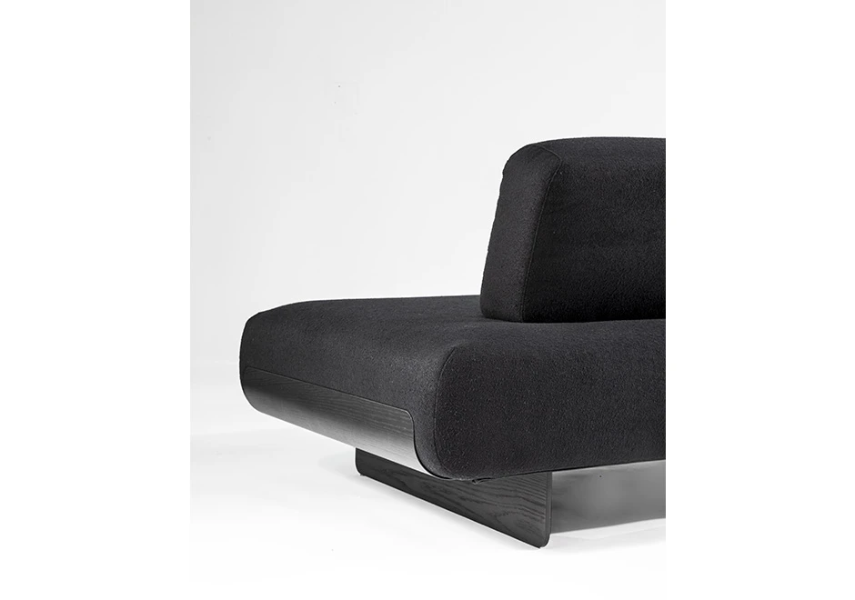 Imagem aproximada de sófa modular, com base de metal, revestido em espuma, estofado em tecido cinza, visto de costas em um fundo branco.