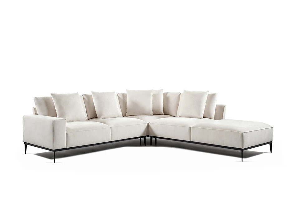 Sofá modular branco, com pés em aço escuro, com diversas almofadas, visto na diagonal, em formato de L, em um fundo branco