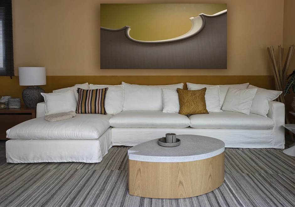 Sofá modular estofado em tecido branco e almofadas decorativas, visto de frente em uma sala moderna.