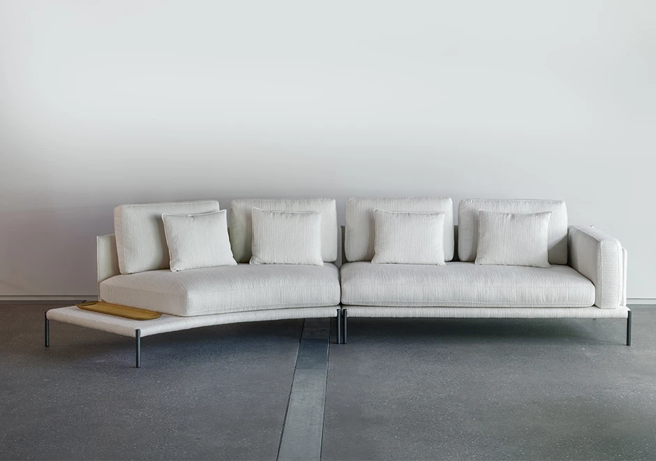 Sofá com escosto com pés de ferro, na cor branca, visto de frente com uma parede branca ao fundo.