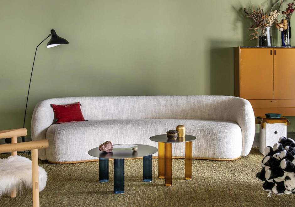 Sofá curvo, estofado em tecido branco, visto de frente, em uma sala aconchegante.