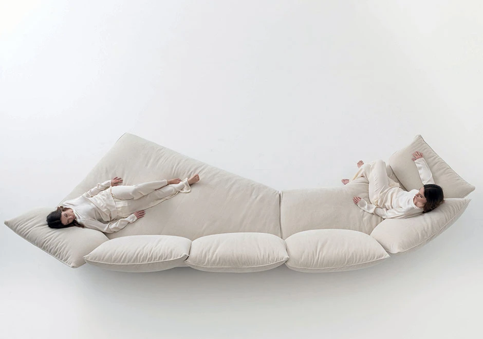 Sofá modular estofado em tecido branco, visto de cima, com duas pessoas sentadas, em um fundo branco.