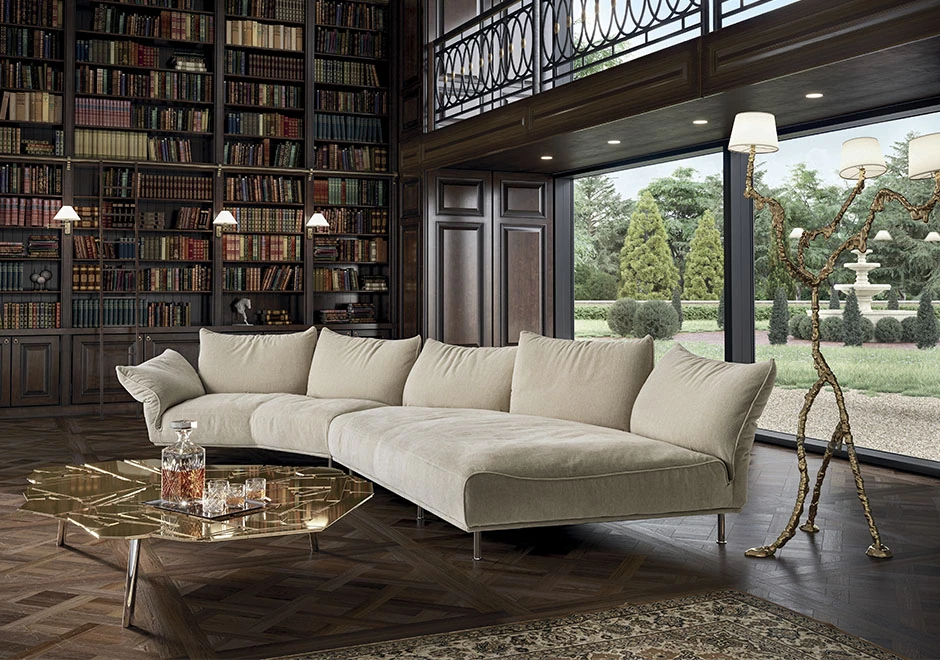 Sofá modular estofado em tecido branco, visto de frente, em uma sala com estantes de livros e uma parede de vidro.