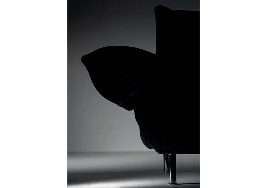 Detalhe de sofá modular estofado em tecido preto, visto de frente.