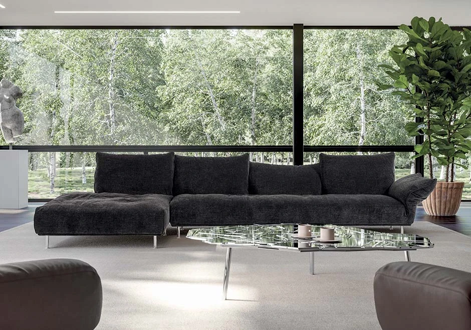 Sofá modular estofado em tecido cinza, visto de frente, em uma sala moderna.