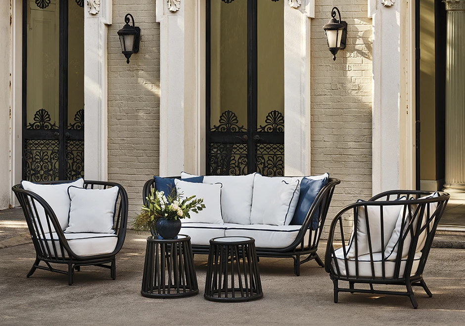 Sofá de área de lazer com estrutura de alumínio e fibra trançada manualmente, tecido na cor branca, visto de lado em uma area externa.