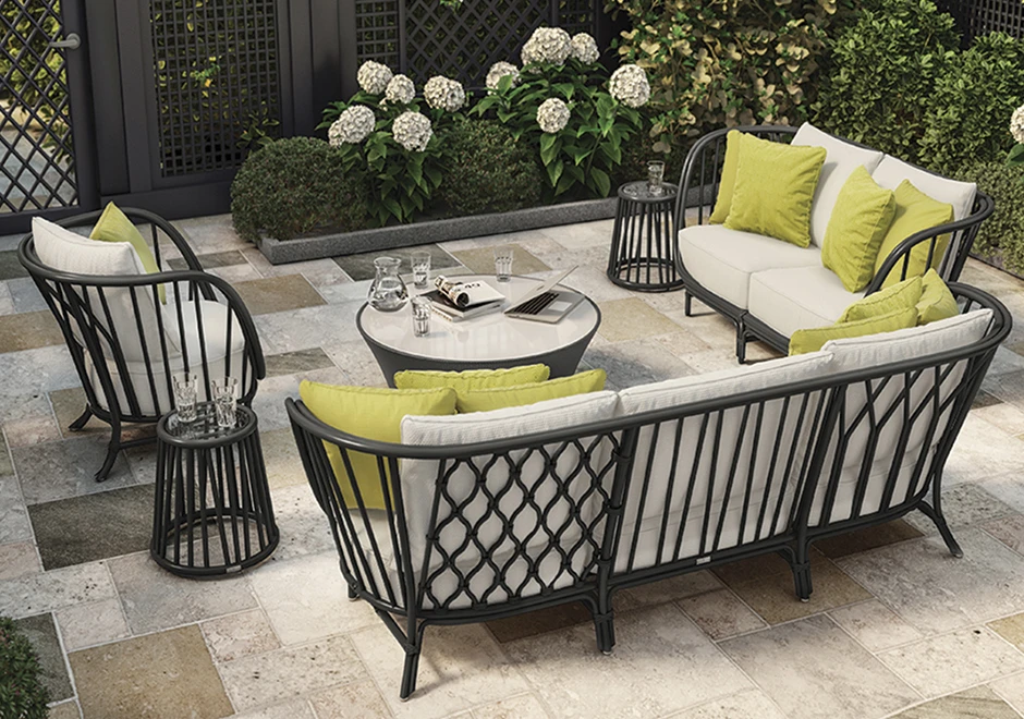 Sofá de área de lazer com estrutura de alumínio e fibra trançada manualmente, tecido na cor branca, visto de costas em uma area externa.