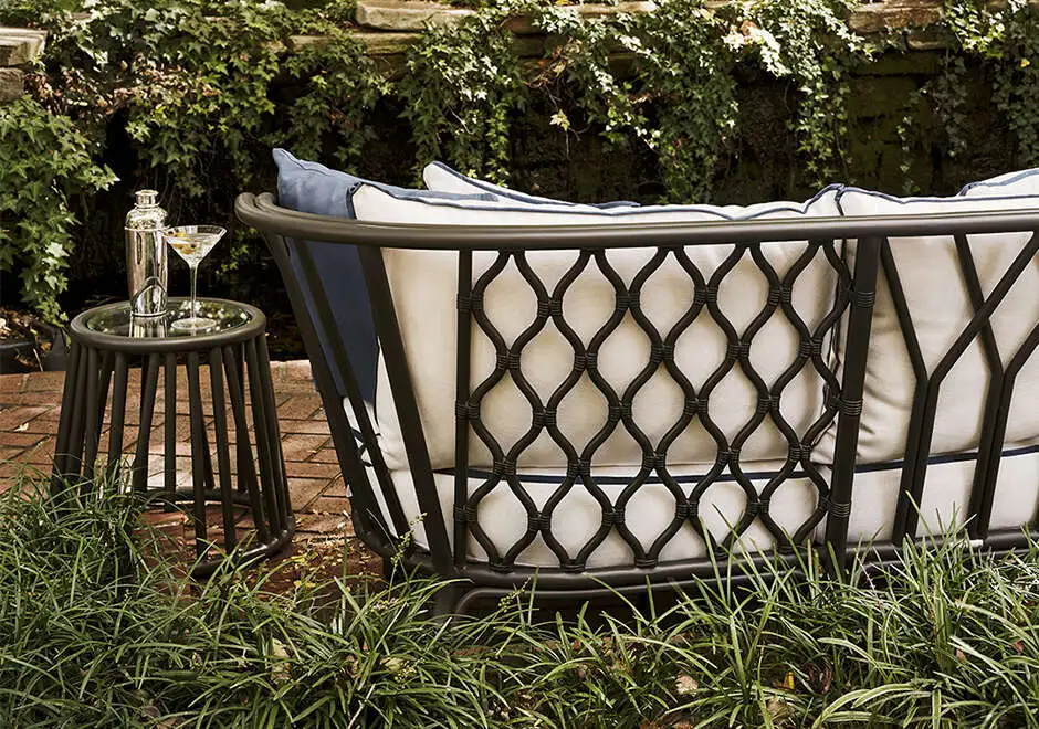 Detalhes de sofá de área de lazer com estrutura de alumínio e fibra trançada manualmente, tecido na cor branca, visto de costas em uma area externa.