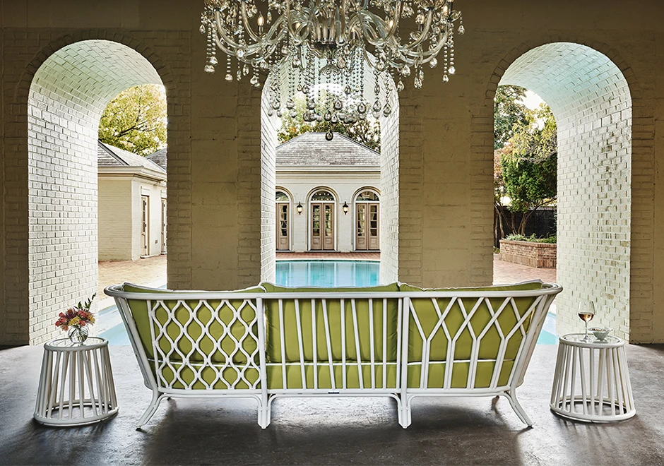 Sofá de área de lazer com estrutura de alumínio e fibra trançada manualmente, tecido na cor verde, visto de costas em uma area externa.