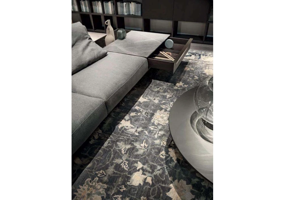 Sofá modular com estrutura de metal, estofado em tecido cinza e almofadas decorativas, visto de cima e com foco em mesa lateral com gaveta e aparador.