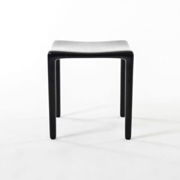 Banco de bar de madeira Tauari ebanizada, visto de frente, em um fundo branco.