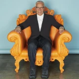 Alessandro Mendini posa em um de seus designs de poltrona.