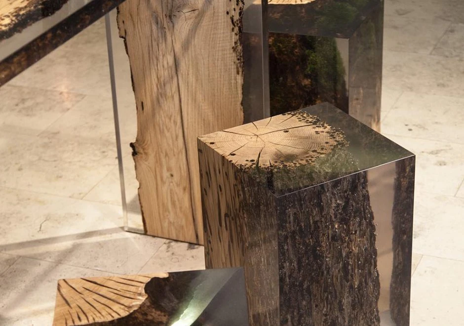 Detalhe de um banco da marca Alcarol de resina transparente e madeira, visto de lado em uma sala moderna.