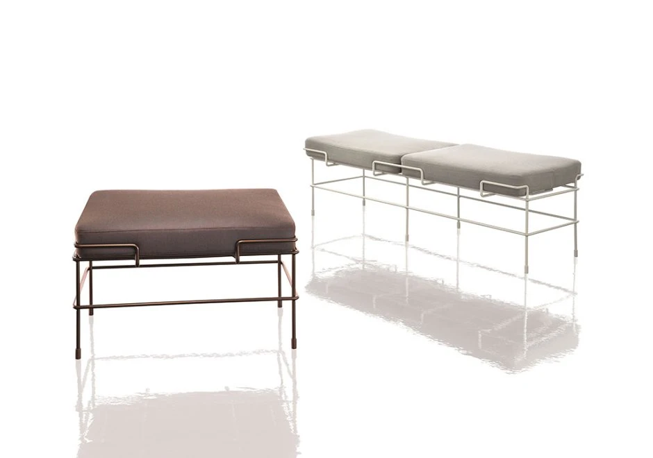 Dois bancos de design com estrutura de aço pintado e almofada de poliuretano expandido com capa de tecido ou couro branco e marrom, vistos de frente, em um fundo branco.