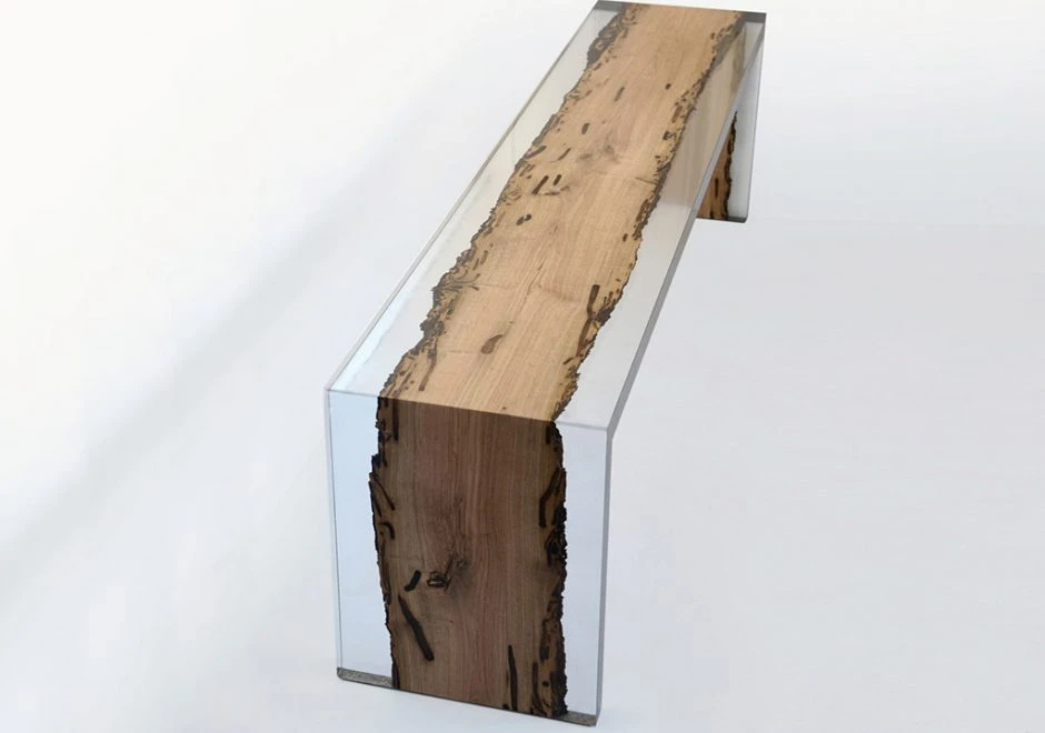 Detalhe de banco de design feito de resina incolor e madeira, visto de cima em um fundo branco.