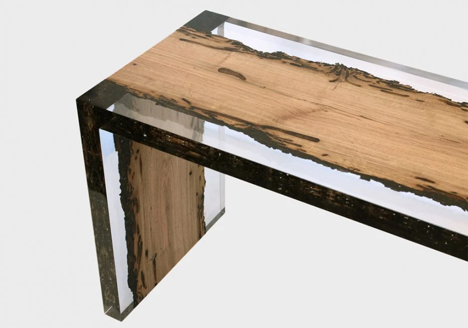 Detalhe de banco de design feito de resina incolor e madeira, visto de frente em um fundo branco.