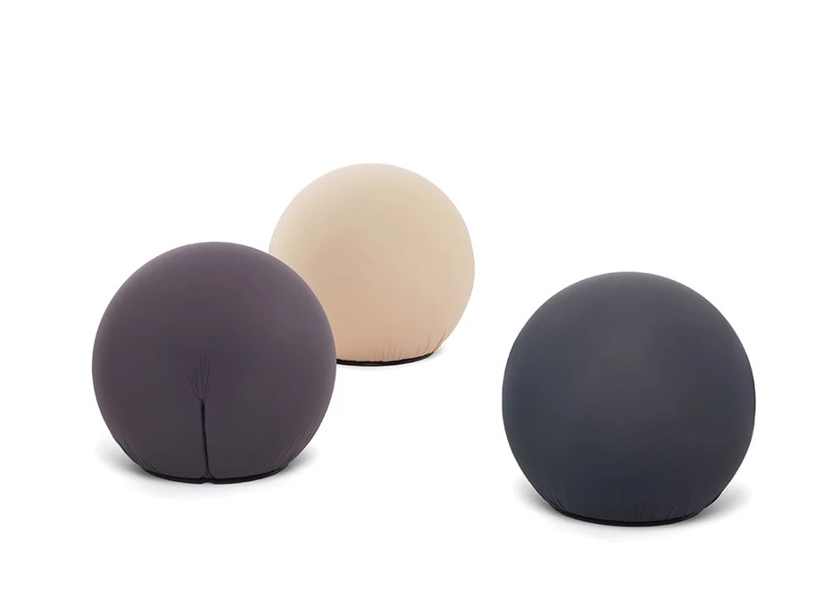 Três pufes lounge com espuma de poliuretano, revestida com capa de tecido elástico, nas cores roxo, bege e cinza, vistos de frente em um fundo branco.