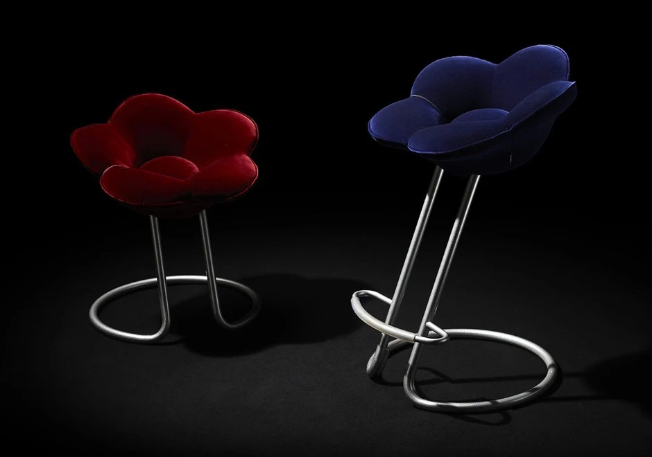 Dois bancos de design com estrutura de metal pintado de cinza metálico e assento de veludo vermelho e azul, vistos de lado em um fundo escuro.