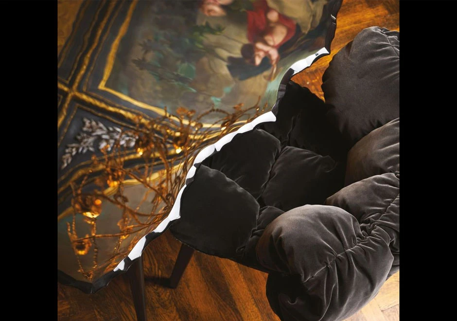 Imagem aproximada de uma cadeira Irmãos Campana com estrutura de madeira na cor preta, assento e encosto de veludo na cor preta em uma sala com uma mesa espelhada.