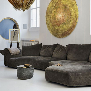 Sofá de design, com estrutura metálica, almofadas e braços reclináveis,cinza escuro, visto de lado em uma sala moderna.