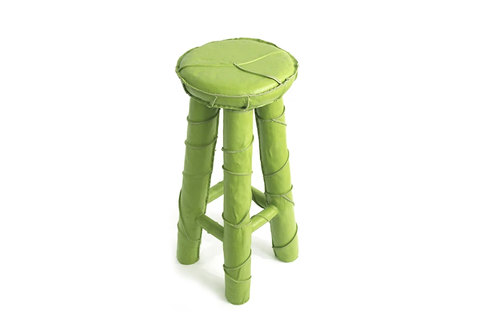 Banco de bar com estrutura de metal revestida em couro verde, visto de frente em um fundo branco.