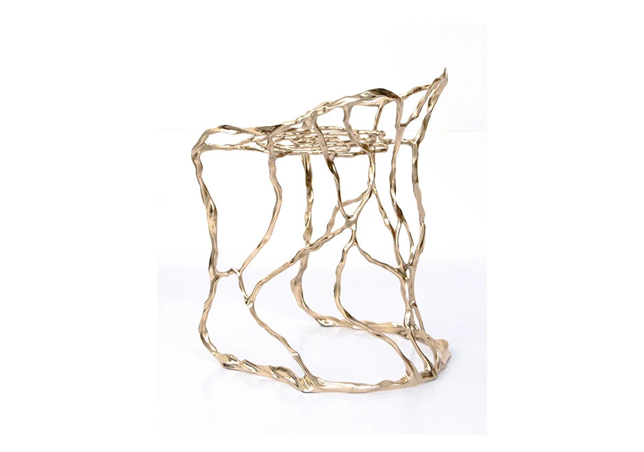 Banco de design em bronze polido ou natural, visto levemente de costas em um fundo branco.