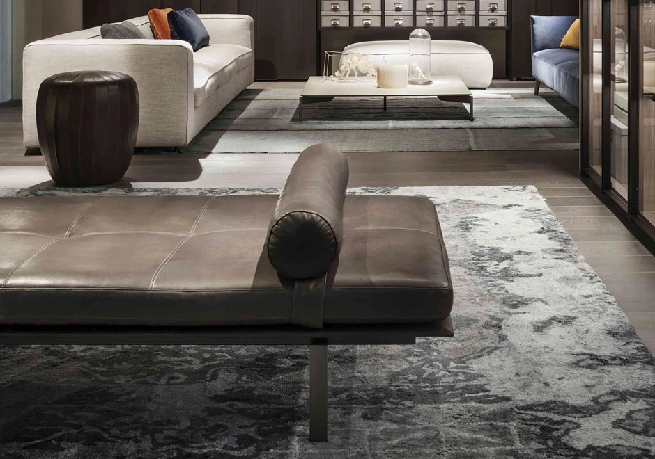 Detalhe de chaise Daybed com estrutura de metal e espuma de poliuretano em couro marrom, visto de lado em uma sala moderna.