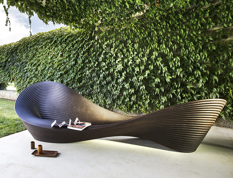 Banco de design de polietileno marrom, visto de frente, em uma area externa.