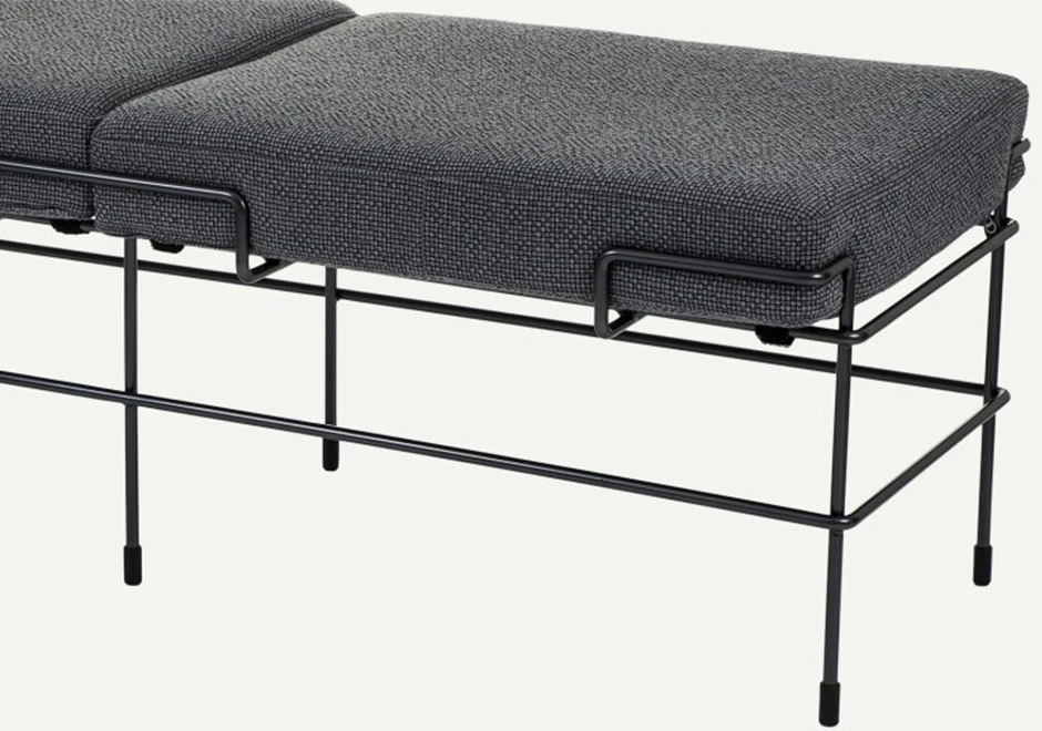 Detalhe de pés de banco de design com estrutura de aço pintado e almofada de poliuretano expandido com capa de tecido ou couro cinza, visto de frente, em um fundo branco.