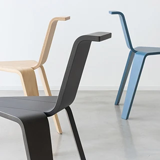 três cadeiras três pés (uma bege, uma preta e uma azul), com três pés cada uma em um fundo branco.