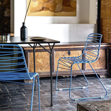 Duas cadeiras empilhaveis com estrutura de alumínio e pintura de poliéster azul em uma sala moderna.