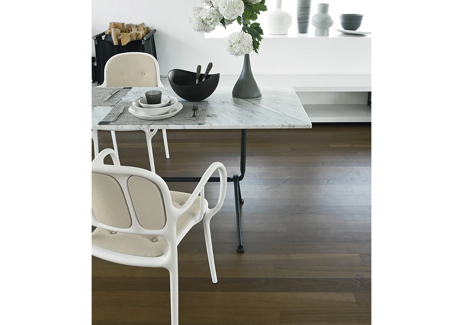 Detalhe de cadeira empilhável assinada, com estrutura de polipropileno e fibras de vidro, com pintura acetinada ,a cor branca, vista de costas em uma sala de jantar.