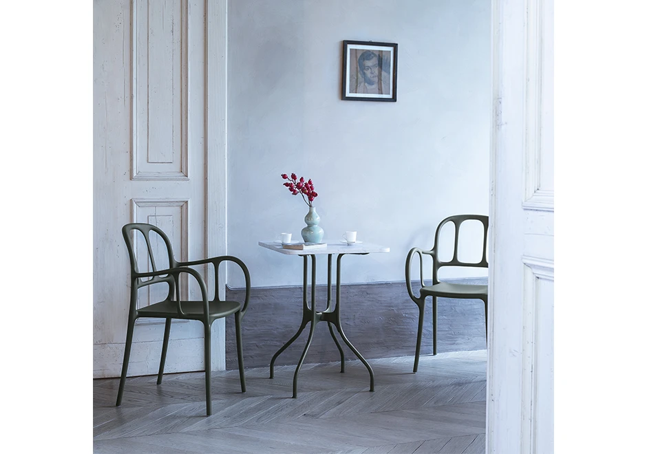 Duas cadeiras empilhaveis assinadas, com estrutura de polipropileno e fibras de vidro, com pintura acetinada, vista de frente em uma sala de jantar.