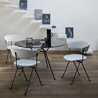 Três cadeiras de design com estrutura de ferro galvanizado ou pintado; assento e encosto de polipropileno em tecido branco, em volta de uma mesa de jantar.