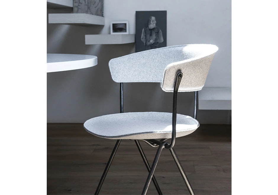 Detalhe de cadeira de design com estrutura de ferro galvanizado ou pintado; assento e encosto de polipropileno em tecido branco, em uma sala.