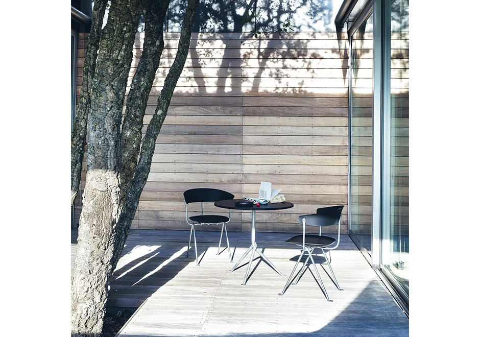 Duas cadeiras de design com estrutura de ferro galvanizado ou pintado; assento e encosto de polipropileno preto, vista de frente em uma sala.