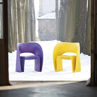 Duas cadeiras de design com estrutura de polietileno roxo e amarelo, uma em frente a outra, em uma area externa.