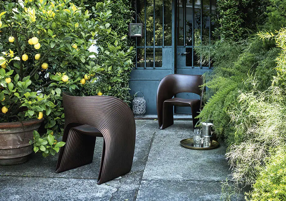 Duas cadeiras de design com estrutura de polietileno marrom, uma em frente a outra, em uma area externa.