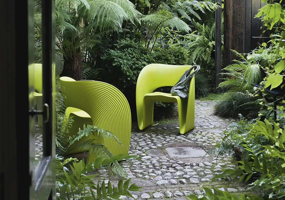 Duas cadeiras de design com estrutura de polietileno verde, uma em frente a outra, em uma area externa.